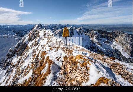 Arrampicatori su una stretta cresta rocciosa nevosa, dietro il crow di picco, vista del panorama di montagna, escursioni a Ammergauer Hochplatte, in autunno, Alpi Ammergau Foto Stock