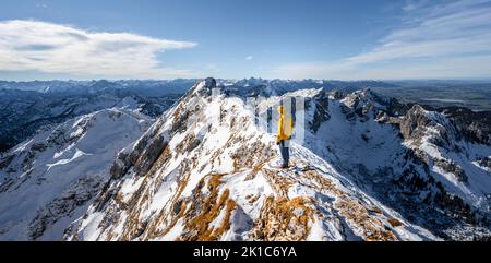 Arrampicatori su una stretta cresta rocciosa nevosa, dietro il crow di picco, vista del panorama di montagna, escursioni a Ammergauer Hochplatte, in autunno, Alpi Ammergau Foto Stock