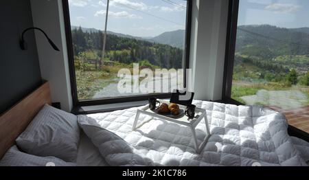 Tavolo per la colazione su letto bianco con vista sulle montagne in Ucraina Foto Stock