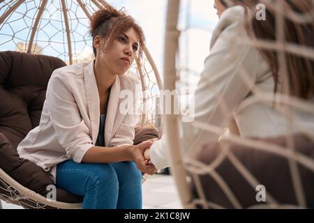 Giovane donna compassionevole sta consolando la sua amica all'aperto Foto Stock
