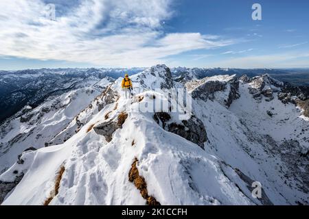 Arrampicatori su una stretta cresta rocciosa nevosa, dietro il crow di picco, vista del panorama di montagna, escursioni a Ammergauer Hochplatte, in autunno, Alpi Ammergau Foto Stock