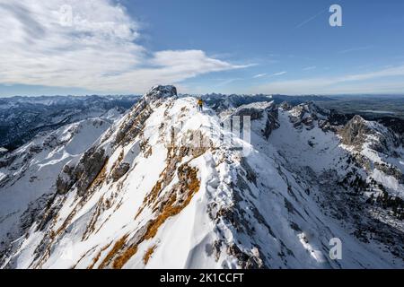 Arrampicatori su una stretta cresta rocciosa nevosa, dietro il crow di picco, vista del panorama di montagna, escursioni a Ammergauer Hochplatte, in autunno, Alpi Ammergau Foto Stock