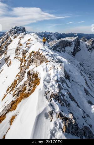 Arrampicatori su una stretta cresta rocciosa nevosa, dietro il crow di picco, vista del panorama di montagna, escursioni a Ammergauer Hochplatte, in autunno, Alpi Ammergau Foto Stock