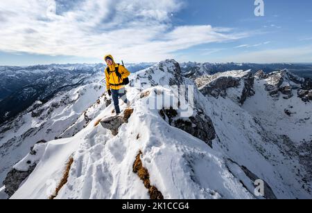 Arrampicatori su una stretta cresta rocciosa nevosa, dietro il crow di picco, vista del panorama di montagna, escursioni a Ammergauer Hochplatte, in autunno, Alpi Ammergau Foto Stock