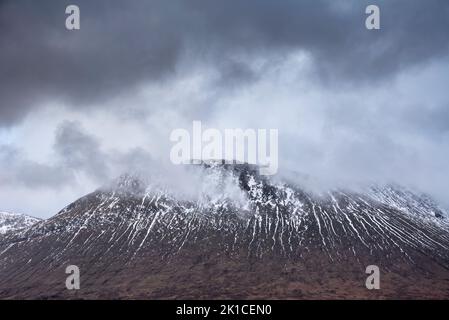 Bella immagine di paesaggio invernale di Beinn A’ Chaladair in Scozia con cieli drammatici in testa Foto Stock