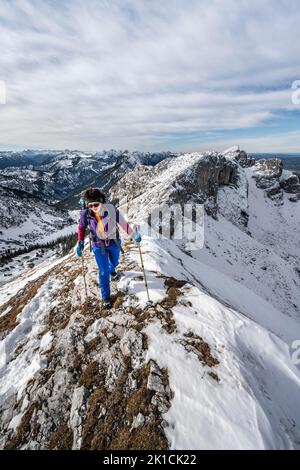 Arrampicatore su una cresta rocciosa innevata, sentiero escursionistico per Ammergauer Hochplatte, vista del panorama montano, dietro il crow di picco, in autunno, Alpi Ammergau Foto Stock