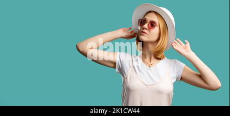 Viaggio di vacanza. Accessori estivi. Bella donna in bianco cappello a contatto isolato su turchese copia spazio. Protezione solare. Abbigliamento alla moda. Vacanza trave Foto Stock