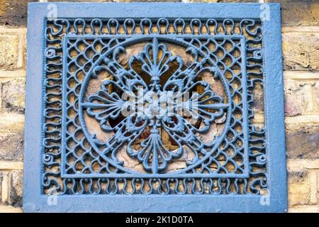 Griglia decorativa in metallo grigio su un muro di mattoni gialli, primo piano Foto Stock