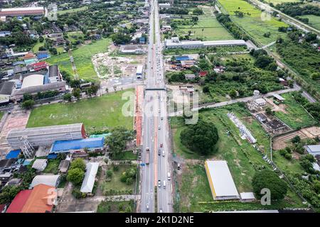 Vista aerea dell'auto che attraversa l'autostrada attraverso il distretto nell'area suburbana circondata da piantagioni Foto Stock