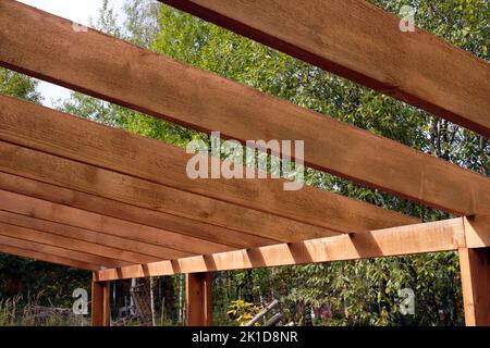 Il processo di costruzione di un baldacchino di legno dalle tavole marroni nella campagna in giorno di estate Foto Stock