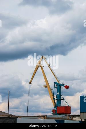 Grandi gru a torre si trovano in un porto fluviale contro un cielo nuvoloso. Foto Stock