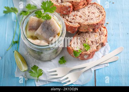 Aringhe marinate fresche e deliziose come fonte di grassi omega. Pesce in vaso servito con pane. Foto Stock