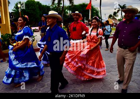 Uomini e donne vestiti tradizionalmente sfilano per le strade di San Pedro, Belize per Noche Centroamericana. Foto Stock