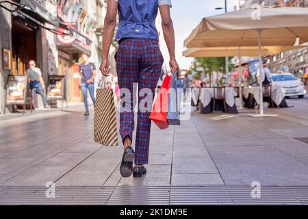 uomo elegante che cammina per la città con borse per lo shopping Foto Stock