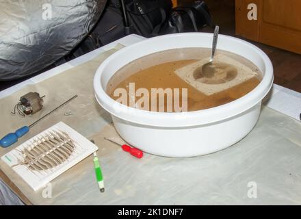 Lavare le parti in plastica di una ventola di scarico della cucina molto sporca in una soluzione acquosa di idrossido di sodio. Foto Stock