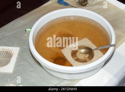 Lavare le parti in plastica di una ventola di scarico della cucina molto sporca in una soluzione acquosa di idrossido di sodio. Foto Stock