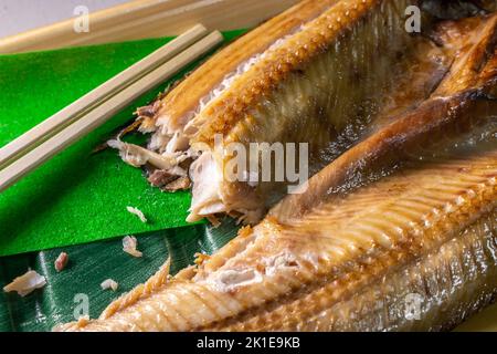 Closeup giapponese Aji no Hiraki (sgombro di cavallo essiccato e salato) in un contenitore di cibo con Waribashi (Hashi). Foto Stock