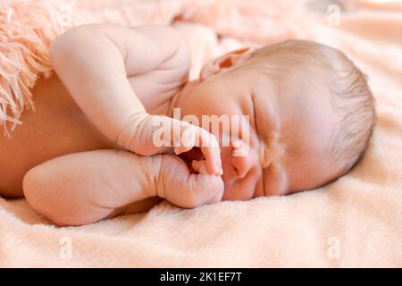 Un bambino neonato cute dorme su un soffice copriletto rosa, un bambino sano e cute dorme dolcemente nei primi giorni della vita Foto Stock