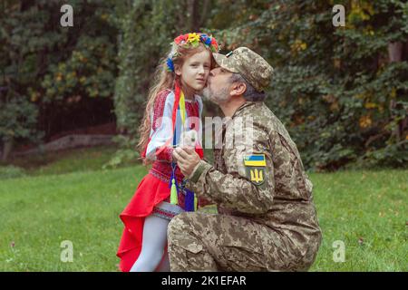 Una bambina Ucraina in costume nazionale incontra suo padre dalla guerra. Foto Stock