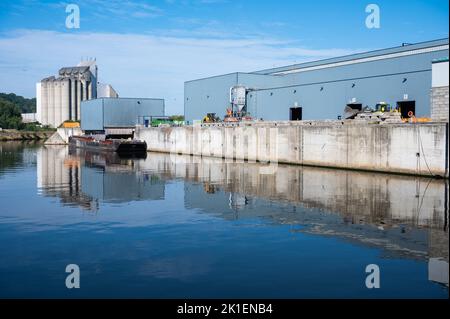 Floreffe, Regione di Wallon, Belgio, 07 28 2022 - stoccaggio industriale di silo e magazzini che si riflettono sulle rive del fiume Sambre Foto Stock