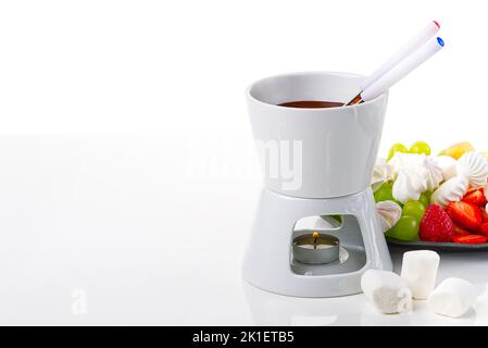 Fonduta di cioccolato. Frutta che si immergia in una ciotola con cioccolato su fondo bianco Foto Stock