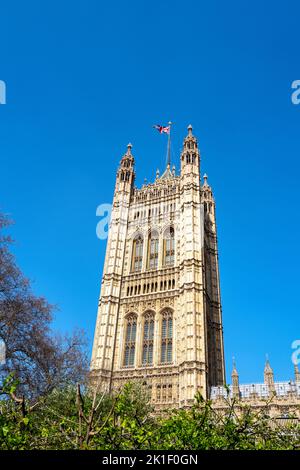 Un Union Jack vola sopra la Victoria Tower, le Houses of Parliament, Londra, Regno Unito, sullo sfondo blu del cielo. Il Palazzo di Westminster è una rinascita gotica Foto Stock