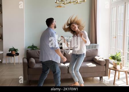 Bella ragazza felice che insegna all'uomo a ballare a casa Foto Stock
