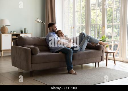 Felice giovane coppia di famiglia che si rilassa su un comodo divano insieme Foto Stock