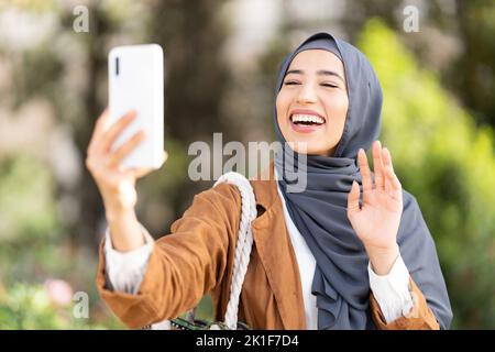 Donna musulmana che sventolava al mobile all'aperto Foto Stock