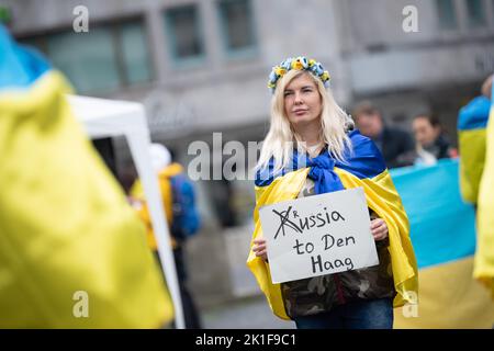 18 settembre 2022, Hessen, Francoforte sul meno: Un partecipante ha in mano un cartello con la scritta "Russia all'Aia" durante una manifestazione a sostegno dell'Ucraina a Goetheplatz. Si tratta di una contro-dimostrazione di una dimostrazione pro-russa su Opernplatz. Foto: Sebastian Gollnow/dpa Foto Stock