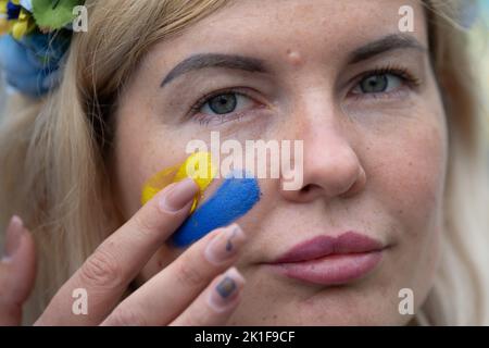 18 settembre 2022, Hessen, Francoforte sul meno: Una donna riceve una bandiera Ucraina dipinta sulla guancia durante una manifestazione a sostegno dell'Ucraina in Goetheplatz. Si tratta di una contro-dimostrazione di una dimostrazione pro-russa sulla Opernplatz. Foto: Sebastian Gollnow/dpa Foto Stock