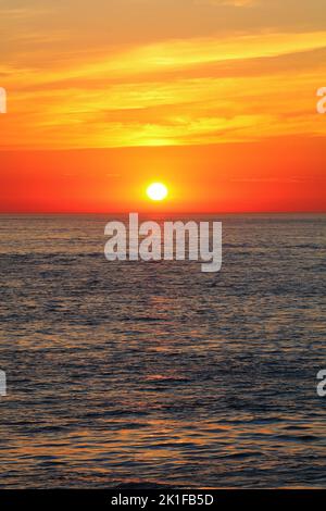 Bellissimo tramonto arancione sull'oceano. Anglesey, Galles del Nord, Regno Unito. Foto Stock