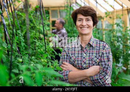 Ritratto di felice donna anziana in posa in serra Foto Stock