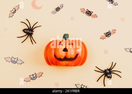 Zucca di Halloween Jack o Lanterna, ragni e pipistrelli su sfondo arancione chiaro. Vista dall'alto, disposizione piatta, spazio di copia. Foto Stock