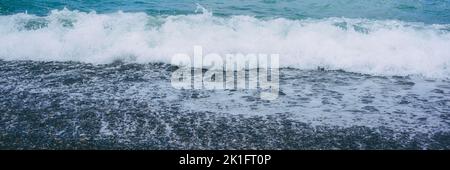 Onde di mare tempestose con spindrift lavaggio spiaggia di ciottoli vuota Foto Stock