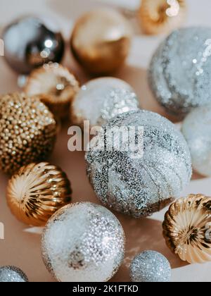 Biglietto di auguri di Natale. Sfondo di palline di Natale diverse. Palline d'oro e d'argento su sfondo beige. Vista frontale, messa a fuoco selettiva Foto Stock