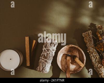 Articoli per la pulizia spirituale - salvia e fiori bundle, palo Santo incenso, candela bianca su sfondo verde. Vista dall'alto. Spazio di copia Foto Stock