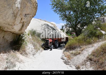 Un trattore rosso su uno stretto sentiero sabbioso tra rocce nella campagna in Cappadocia, Turchia Foto Stock