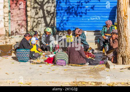 Famiglia e amici gustando un pasto fuori dalla porta del monastero di Pelkor Chode nella città di Gyantse, nella prefettura di Shigatse, Tibet, Cina Foto Stock