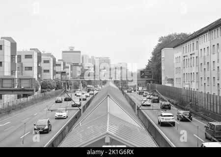 Un colpo in scala di grigi dell'autostrada Bundesautobahn 40 attraverso la città di Essen in Germania con le automobili da entrambi i lati di esso Foto Stock