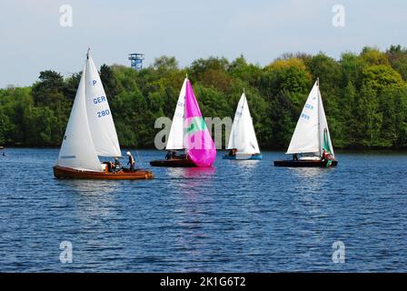 Quattro barche a vela sul Six Lakes Plateau a Duisburg, Germania, con lussureggianti alberi verdi intorno alle acque blu brillante Foto Stock