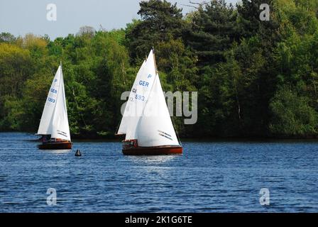 Due barche a vela sull'altopiano dei sei Laghi a Duisburg, Germania, con lussureggianti alberi verdi intorno all'acqua blu brillante Foto Stock