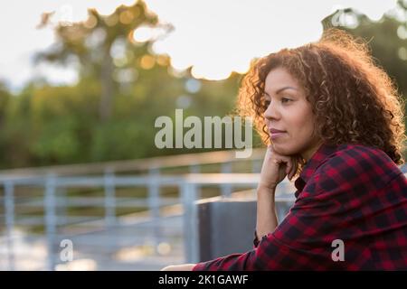 Donna in trent'anni che pensa come il sole tramonta. Foto di alta qualità Foto Stock