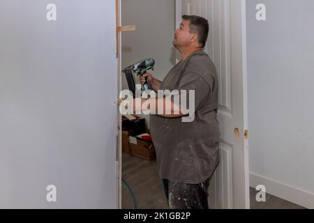 Le porte interne di una nuova casa sono state installate da un addetto al rivestimento del falegname Foto Stock