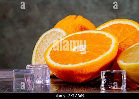 Limoni e arance con ghiaccio. Preparazione di un cocktail di agrumi. Foto Stock