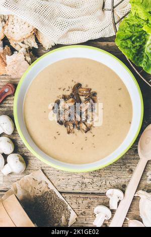 Zuppa vegana mista di funghi button. Servito su un tavolo di legno. Ingredienti e insalata fresca come decorazione. Alimenti senza glutine adatti per celiaci. Foto Stock