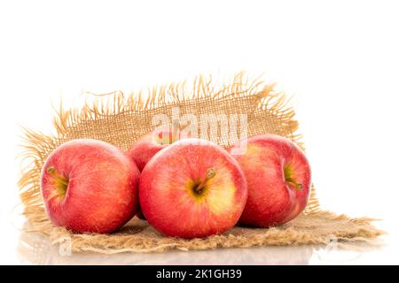Quattro mele rosse mature su tovagliolo di iuta, macro, isolate su fondo bianco. Foto Stock