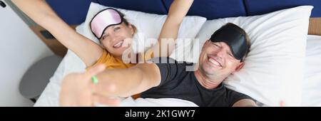 Uomo e donna sorridenti si svegliano a letto Foto Stock