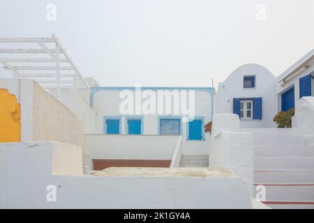 Colorato giallo, blu e bianco lavano le case e le ville tradizionali stucco nel villaggio di Oia sull'isola greca, di Santorini, Grecia su una nebbia, Foto Stock