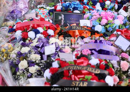 Dopo la scomparsa del Monarca britannico, la gente depone fiori in un murale raffigurante la Regina Elisabetta II sulla Shankill Road a Belfast. Foto Stock